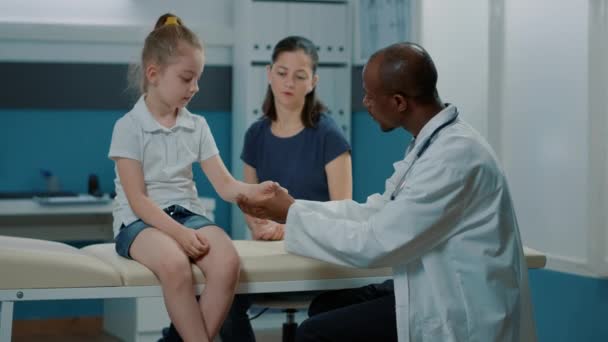 Pediatrician consulting little child with injured arm at recovery appointment — Stock Video