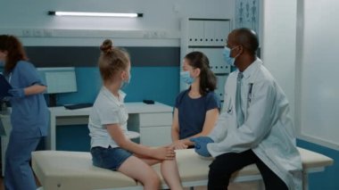 Afrikalı Amerikalı doktor küçük çocuklara ve ebeveynlerine ilaç veriyor.