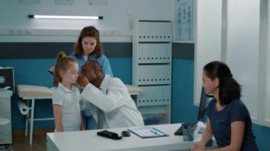 Doktor kabinede kulak muayenesi yapmak için otoskop kullanıyor.