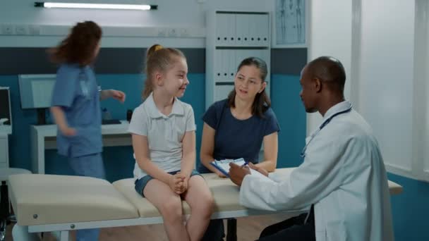 Μικρό κορίτσι και γιατρός που κάνουν ιατρικές συμβουλές στο γραφείο — Αρχείο Βίντεο