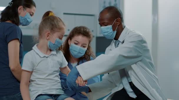 Equipo médico diverso que aplica bandaid en niño con brazo fracturado — Vídeo de stock