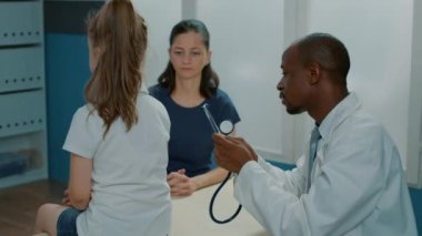 Doktor kalp atışlarını ölçmek için steteskop kullanıyor.