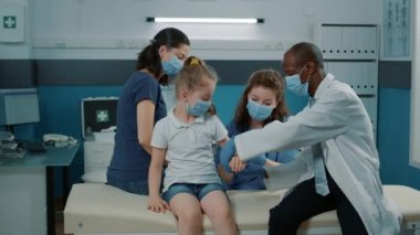 Çocuk doktoru muayenede yaralı çocuğun koluna bandaj takıyor.