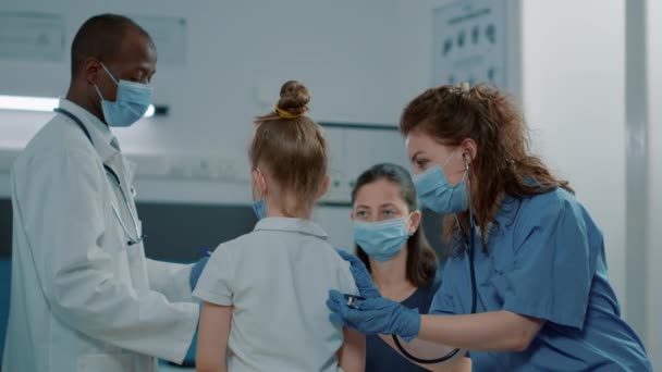 Assistente médico consultando criança pequena com estetoscópio — Vídeo de Stock