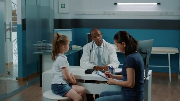 Médico dando documentos de check-up na área de transferência para a mãe — Vídeo de Stock