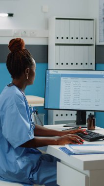 Dolabındaki bilgisayar klavyesinde yazan tıbbi asistan