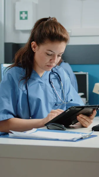 Assistant médical tapant sur l'écran de la tablette et vérifiant l'ordinateur — Photo