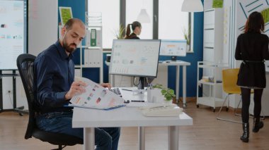 İşletme yöneticisi çizelgeli bilgisayar ve kağıtları kullanıyor