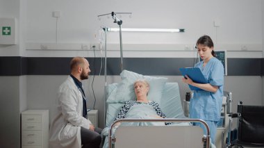 Tıbbi ekip eski bir hastayla yatakta istişare yapıyor.