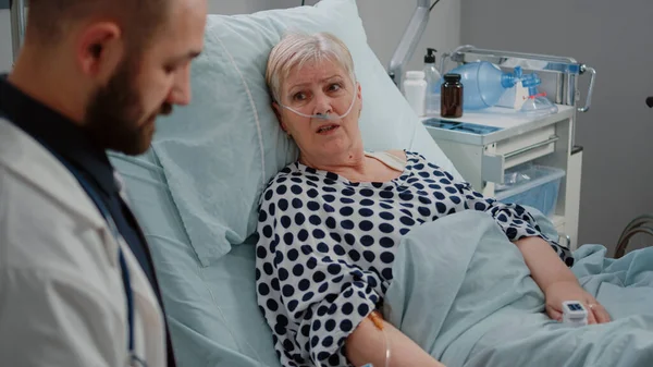 Sluiten van oudere patiënt in bed en praten met medic — Stockfoto