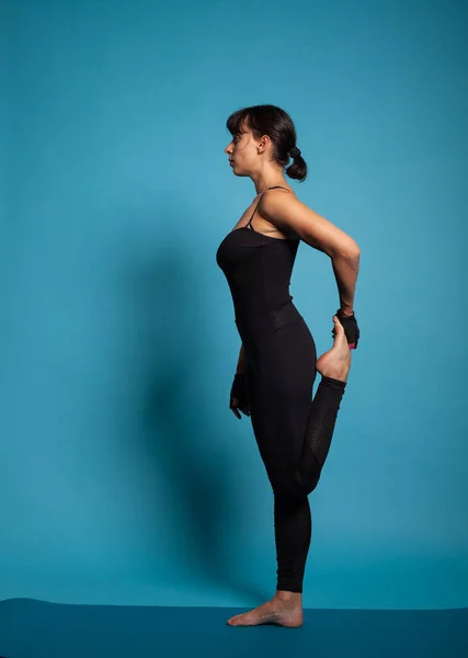 Donna caucasica in abbigliamento sportivo in piedi su yoga stuoia stretching gamba — Foto Stock