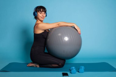 Refah içinde çalışırken kulaklık kullanarak müzik dinleyen kişisel antrenör.