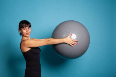 Gülümseyen antrenör spor topu tutuyor vücut kaslarını geriyor.