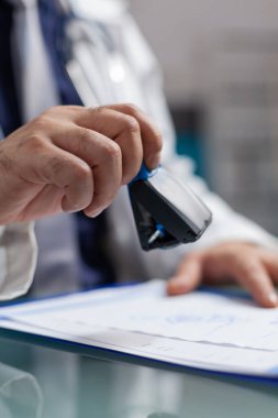 Pratisyen hekimin eli reçeteli kağıtta tıbbi damga kullanıyor.