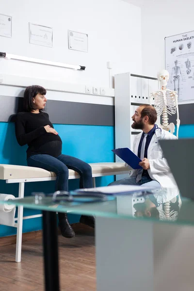 Förväntad kvinna pratar med läkare vid kontrollbesöket — Stockfoto