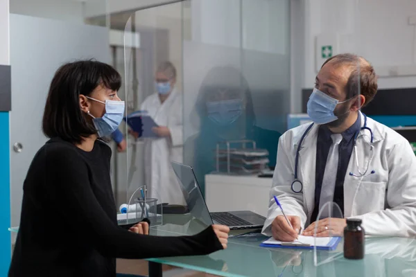 Hälsospecialist antecknar vid läkarkonsultation på kontoret — Stockfoto