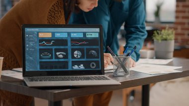 Masanın üzerinde veri oranı çizelgeleri olan dizüstü bilgisayarın ekranını kapat