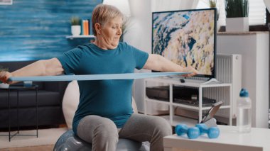 Zindelik tonlama topunda direnç bandını çeken yaşlı bir insan.