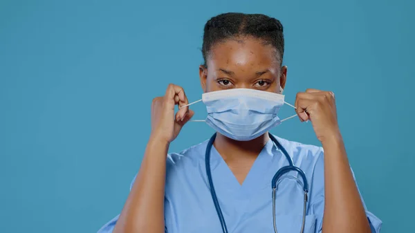 Close-up van vermoeide medische assistent nemen masker van gezicht — Stockfoto