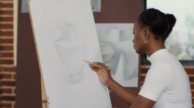 Beyaz tuval üzerine vazo çizen Afrikalı Amerikalı kadın.