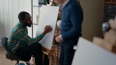 Sanat sınıfı öğrencilerine yeni çizim tekniği öğreten yaşlı bir sanatçı.