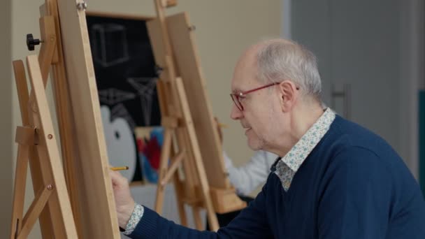 Çizim becerilerini öğrenmek için kalem kullanan kıdemli bir adamın portresi. — Stok video