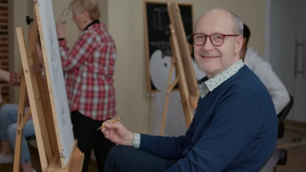 Retrato de homem sênior desfrutando de aula de arte para desenvolver habilidades de desenho — Vídeo de Stock