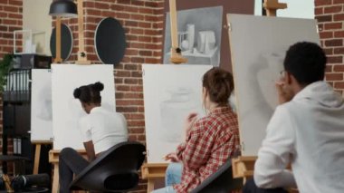 Büyük öğretmen genç öğrenciye vazo çizimi için rehberlik ediyor.