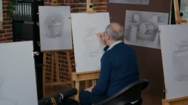 Genç öğretmen yaşlı adama vazo başyapıtında yardım ediyor.