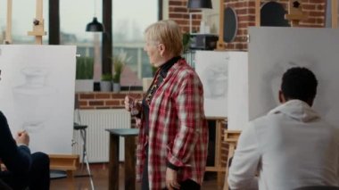 Sanat dersinde tuvale resim çizen son sınıf öğrencisini denetleyen sanatçı.