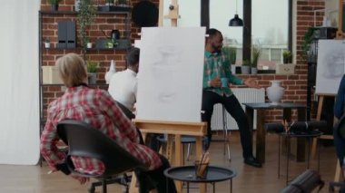 Genç adam yaratıcı insanlara tuvale resim çizmeyi öğretiyor.