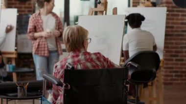 Tekerlekli sandalyedeki son sınıf öğrencisi sanat sınıfında ilham modeli çiziyor.