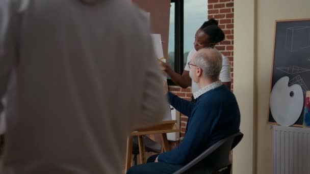 Lehrer und Schüler helfen alten Mann, Vase auf Leinwand zu malen — Stockvideo
