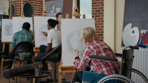 Старшая женщина в инвалидной коляске рисует вазу карандашом — стоковое видео