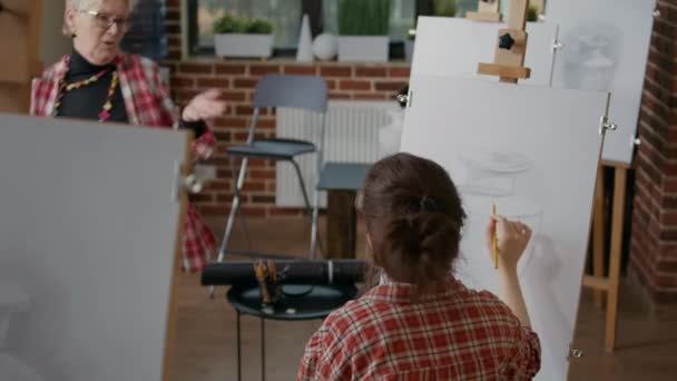 Jonge vrouw ontvangt tekenadvies van docent in kunstklas — Stockvideo
