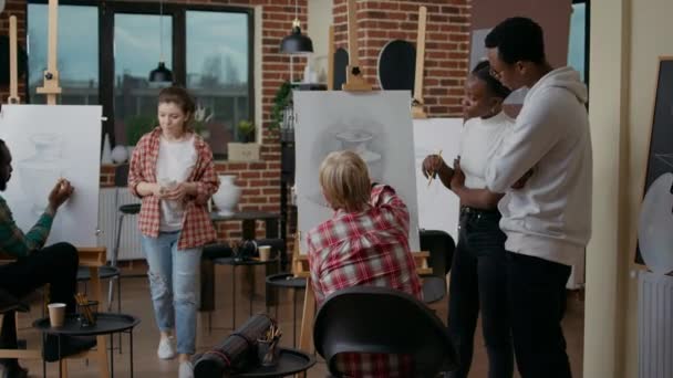 Estudantes ajudando a mulher idosa com vaso desenhando sobre tela — Vídeo de Stock