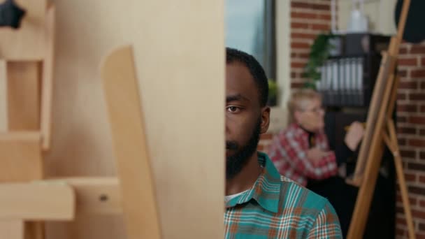 Portret van een Afrikaans-Amerikaanse man op doek in de kunstklas — Stockvideo