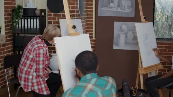 Professor mais velho explicando técnica de desenho para alunos em aula de arte — Vídeo de Stock