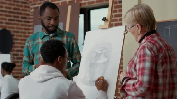 Učitel a tým studentů mluví o kreslení vázy na plátně — Stock video