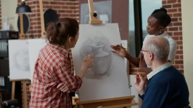 Sanat sınıfındaki öğrencilerle resim tekniği hakkında konuşan bir öğrenci.