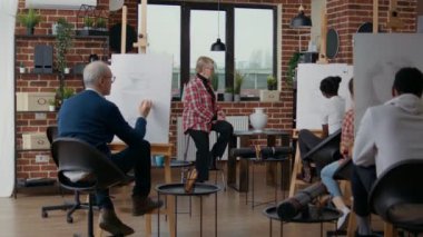 Sanat sınıfındaki insanlara sanatsal görüşü anlatan kıdemli bir kadın.