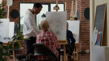 Erkek öğretmen çizim sınıfındaki yaşlı kadına tavsiye veriyor.