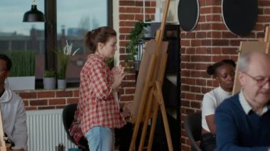 Sanat sınıfı programında resim çizen insanlara bakan genç bir sanatçı