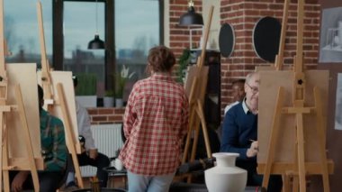 Sanat dersi öğretmeni vazo modeli çizen öğrencileri denetliyor.