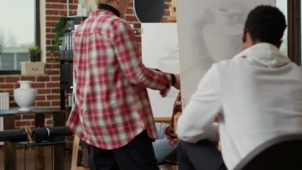 Äldre konstnär hjälpa unga student med vas modell ritning — Stockvideo