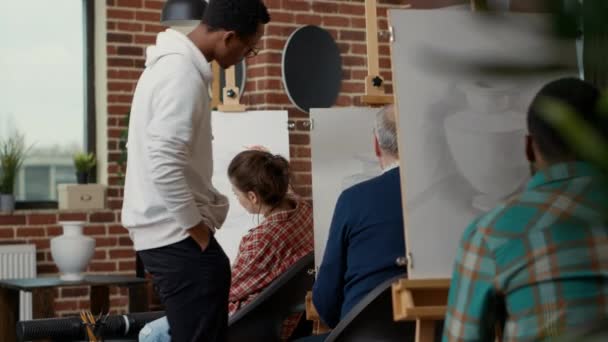 Junger Mann betrachtet ältere Studentin beim Zeichnen von Vasenmodell — Stockvideo