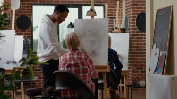 Male teacher giving advice to elder woman in drawing class — Stock Video