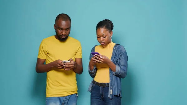 Pareja afroamericana usando smartphone para enviar mensajes de texto en estudio — Foto de Stock
