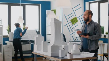 Yapı modelinin yapısını planlamak için tabletle çalışan adam mimar