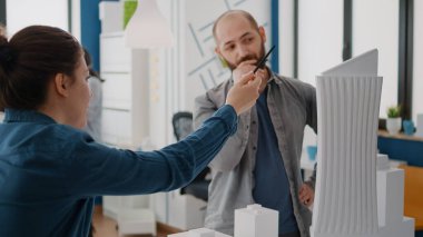 Erkeklerle fikir alışverişinde bulunan bir kadın model planlar ve planlar tasarlıyor.